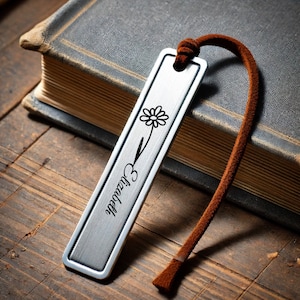 May include: Silver bookmark with a flower design and the word "Elizabeth" engraved on it. The bookmark has a brown leather tassel.
