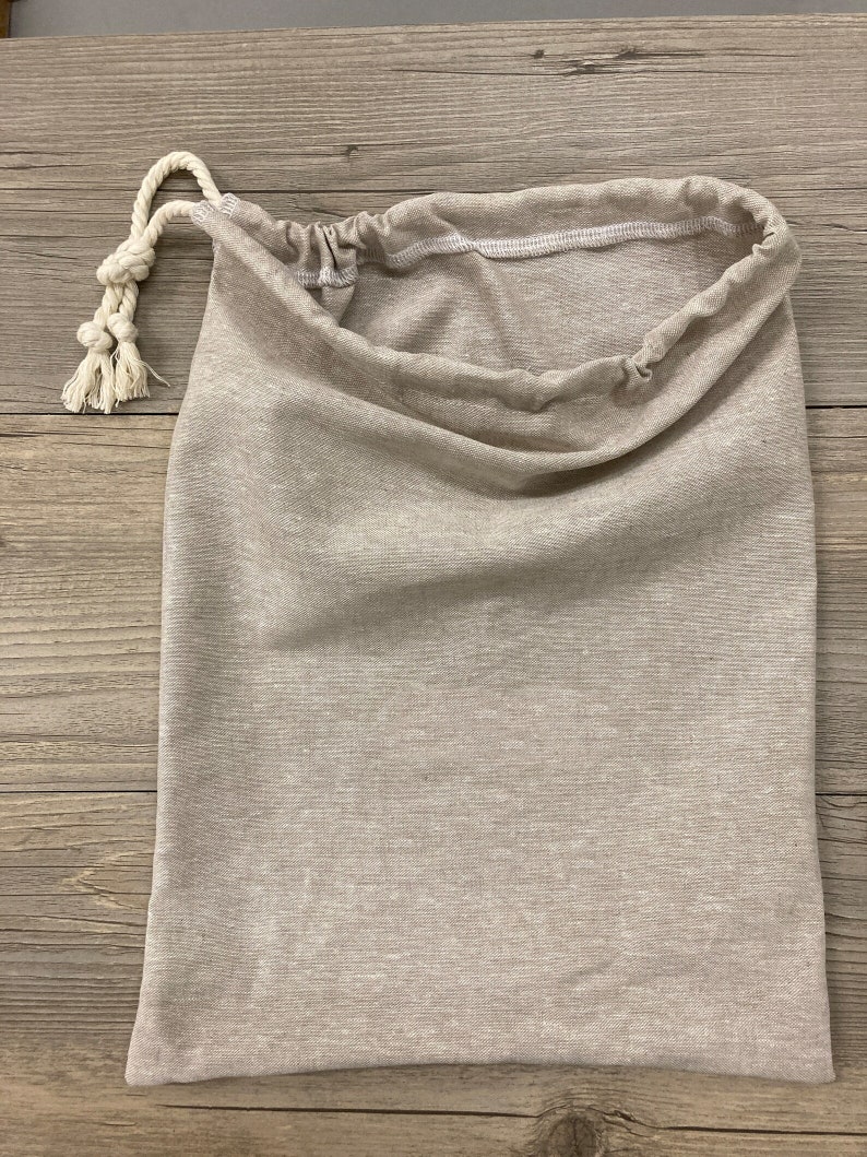 May include: A beige drawstring bag made of a soft, textured fabric. The bag has a white drawstring closure and is perfect for storing small items.