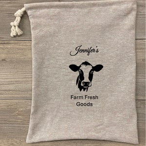 May include: A gray canvas bag with a black cow illustration and the text "Jennifer's Farm Fresh Goods".