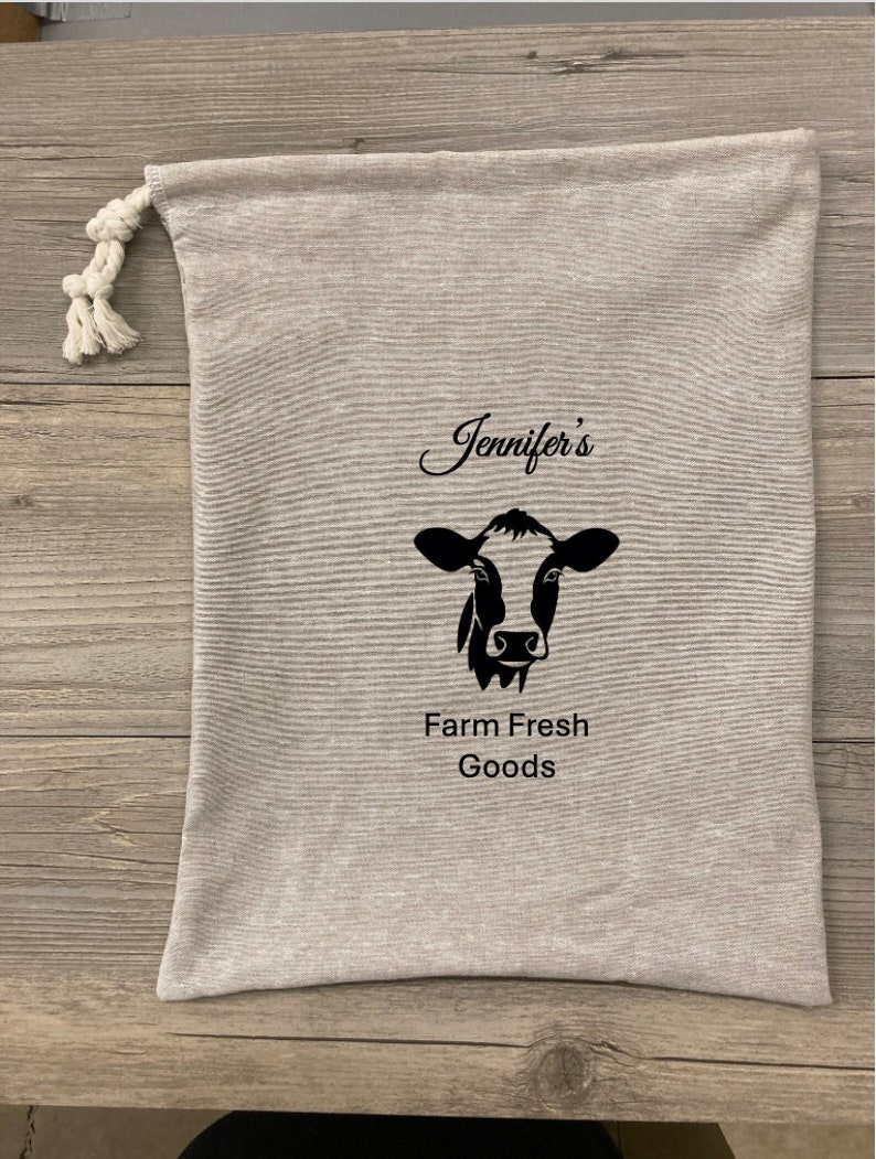 May include: A gray canvas bag with a black cow illustration and the text "Jennifer's Farm Fresh Goods".