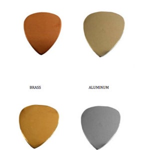 May include: Four guitar picks made of different metals: copper, sterling silver, brass, and aluminum. Each pick is shaped like a standard guitar pick with a pointed tip.