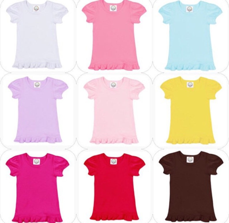 May include: Nine short-sleeved t-shirts in various colors, including white, pink, light blue, lavender, yellow, fuchsia, red, and brown. Each shirt has a ruffled hem and puff sleeves. A small logo is visible on the upper chest of each shirt.