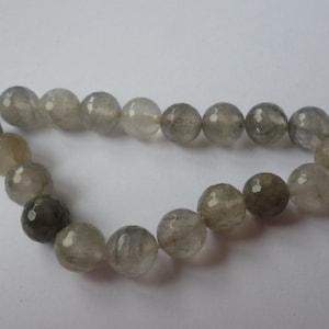 Könnte beinhalten: Eine Strähne grauer facettierter Edelsteinperlen. Die Perlen sind rund und haben ein durchscheinendes Aussehen.