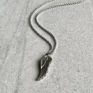 May include: A silver chain necklace with a silver wing pendant. The chain is a delicate, box chain style.