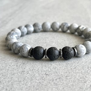 May include: A gray and black beaded bracelet with black lava rock beads and silver metal spacers.