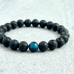 May include: A black lava rock beaded bracelet with a single blue tiger's eye bead.