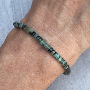 May include: A turquoise and black beaded bracelet with a simple design. The bracelet is made of small, round beads that are strung together on a thin cord.