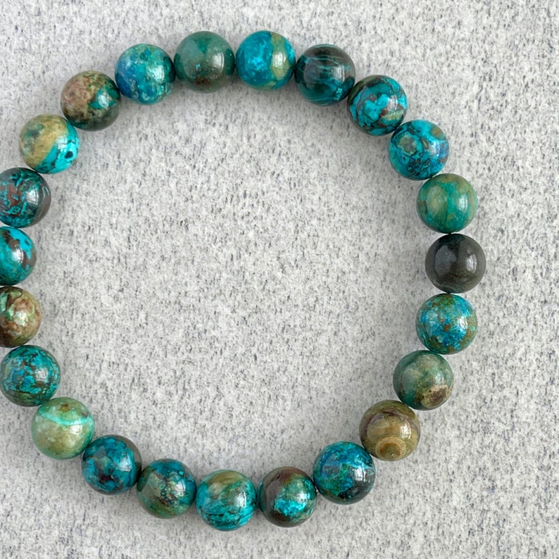 Puede incluir: Un brazalete de piedras preciosas turquesa y verde con cuentas redondas. El brazalete est&aacute; hecho de piedras naturales y tiene un aspecto &uacute;nico y terroso.