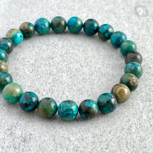 Puede incluir: Un brazalete de piedras preciosas turquesa y verde con cuentas redondas.