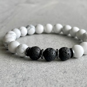 Könnte beinhalten: Ein weißes und schwarzes Perlenarmband mit schwarzen Lavasteinen und silbernen Zwischenstücken.