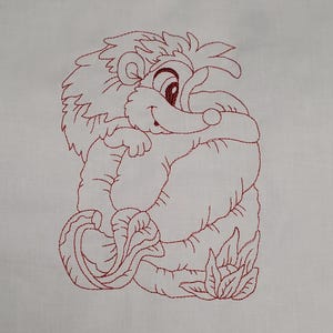 Puede incluir: Un diseño bordado en rojo de un león de dibujos animados abrazando un objeto grande y redondo. El león tiene una cara sonriente y está rodeado de hojas. El bordado está sobre un fondo blanco.