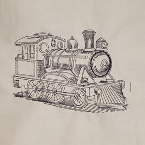 May include: Embroidered black and white train design. The train features a detailed engine, passenger car, and wheels. The design is on a cream-colored fabric, creating a classic, vintage aesthetic. The embroidery work is intricate and well-defined.