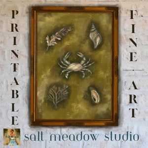 May include: A framed painting with a green background featuring a crab, a feather, a seashell, and seaweed. The frame is gold and the painting is titled "salt meadow studio".
