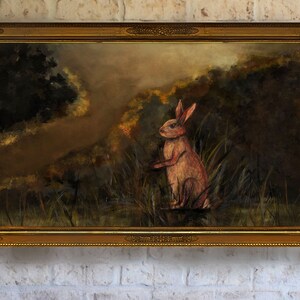May include: A framed oil painting depicting a pink rabbit sitting in a field of tall grass. The background is a hazy forest with a dark green tree on the left side of the painting.