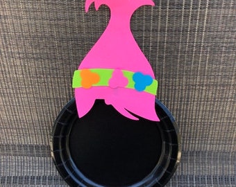 May include: A black paper plate with a pink felt troll hair topper. The topper has a green headband with orange, green, and blue felt flowers.