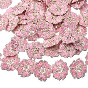 May include: A collection of pink and gold lace flower embellishments. The flowers are delicate and intricate, with a scalloped edge. They are perfect for adding a touch of elegance to any craft project.