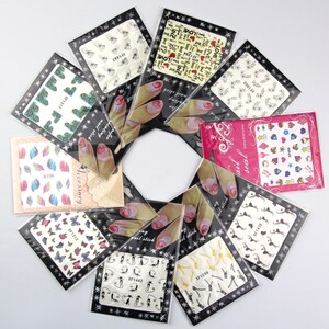 May include: Assortment of nail art stickers in various designs, including butterflies, peacocks, leaves, and hearts. The stickers are packaged in clear plastic bags with black borders and white text.
