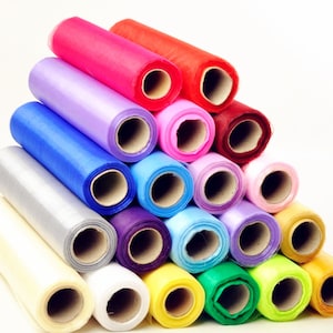 Puede incluir: Un conjunto de rollos de tul de colores en varios tonos de rosa, morado, azul, verde, amarillo y blanco. Los rollos están dispuestos en forma de pirámide, con el rollo más grande en la parte inferior y el más pequeño en la parte superior.