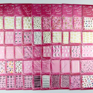 May include: Thirty-nine sheets of nail art stickers with various designs, including stars, crowns, hearts, and geometric patterns. The stickers are packaged in individual clear plastic bags with pink borders and the text "3D Nail Seal" printed on each bag.