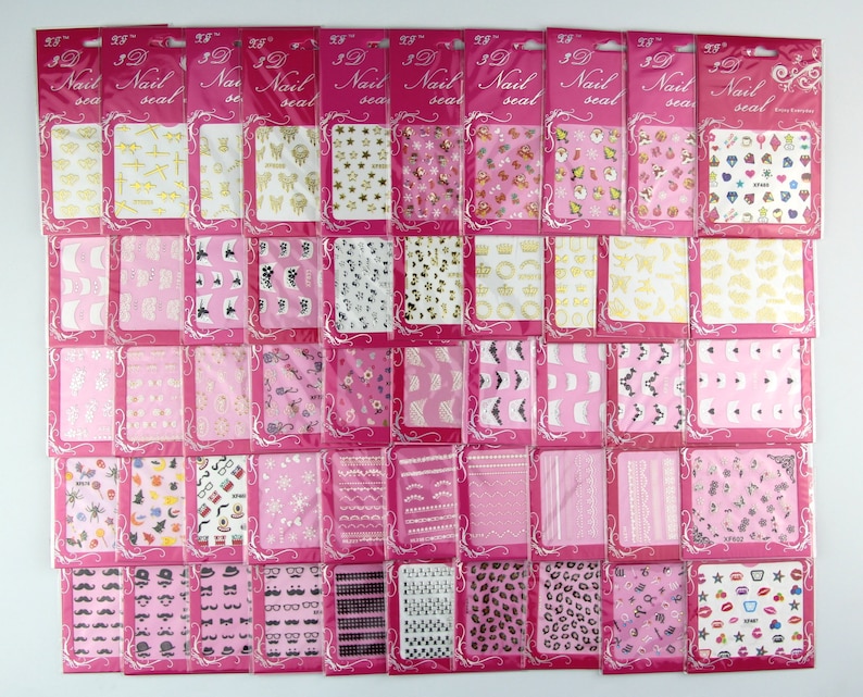 May include: Thirty-nine sheets of nail art stickers with various designs, including stars, crowns, hearts, and geometric patterns. The stickers are packaged in individual clear plastic bags with pink borders and the text "3D Nail Seal" printed on each bag.