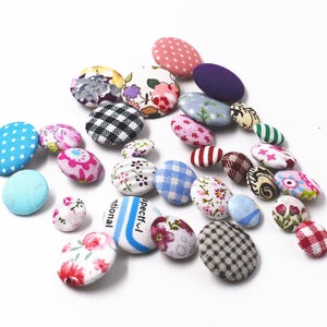 May include: Assortment of colorful fabric covered buttons with various patterns, including polka dots, stripes, and floral designs.