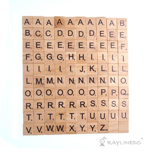 May include: A collection of square wooden tiles arranged in a grid, each featuring a black printed letter and a corresponding numerical point value. The set includes various letters of the alphabet, such as A, B, C, D, E, F, G, H, I, J, K, L, M, N, O, P, Q, R, S, T, U, V, W, X, Y, and Z, with some letters repeated across multiple tiles.