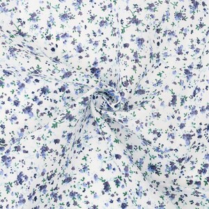 K&ouml;nnte beinhalten: Wei&szlig;er Stoff mit einem zarten Blumenmuster. Das Design zeigt kleine, verstreute blaue und violette Blumen mit gr&uuml;nen Bl&auml;ttern. Der Stoff ist dicht gewebt und scheint aus Baumwolle oder einem &auml;hnlichen Material zu bestehen, geeignet f&uuml;r N&auml;hprojekte.