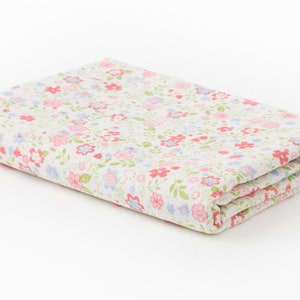 May include: A folded white fabric with a small pink and blue floral pattern.