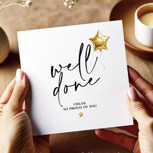 May include: A white card with the words "well done" in black script, a gold star balloon illustration, and the text "CHLOE SO PROUD OF YOU". The card is held by hands with manicured nails. The card also has a small gold star.