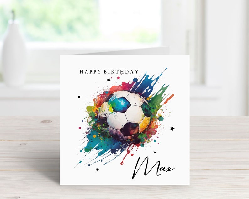 May include: A white card with a colorful watercolor design of a soccer ball and the words "Happy Birthday Max".