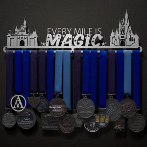 May include: A silver metal medal display rack with two castle silhouettes on either side. The rack has the words "Every Mile Is Magic" in the center. The rack is holding a variety of medals with different designs.