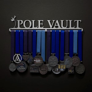 May include: A silver metal medal display rack with the words "POLE VAULT" on it. The rack has 15 medal hangers and is holding a variety of silver and black medals with blue ribbons.