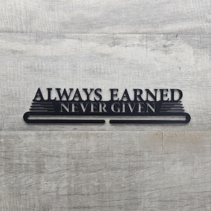 May include: Black metal medal hanger with the text "ALWAYS EARNED NEVER GIVEN".