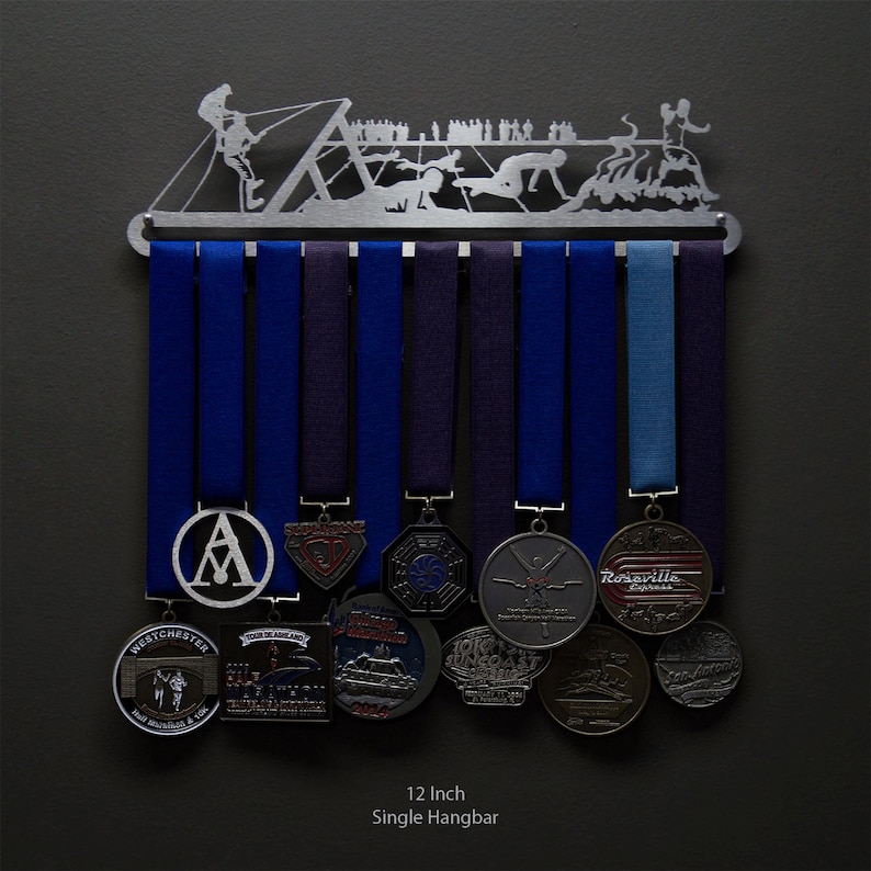 Puede incluir: Un colgador de medallas individual de 30,5 cm con un dise&ntilde;o de metal plateado de un grupo de personas participando en un deporte acu&aacute;tico. El colgador tiene ocho ganchos para colgar medallas. El colgador se muestra sobre un fondo gris oscuro.