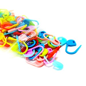 Peut inclure: Un sac en plastique rempli de marqueurs de points en plastique de différentes couleurs. Les marqueurs sont de formes variées, notamment des cercles, des ovales et des crochets.