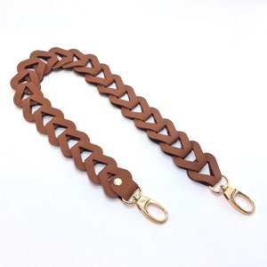 May include: Brown leather bag strap with a braided design and gold metal clasps.