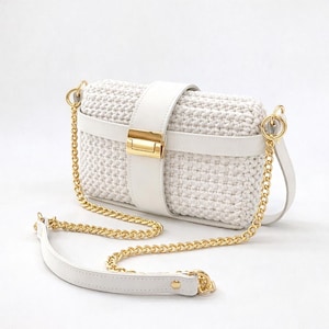 May include: A white, rectangular crossbody bag with a woven texture. It features a white leather strap and gold-colored chain and hardware. The bag has a gold clasp closure and a long chain strap for shoulder or crossbody wear.