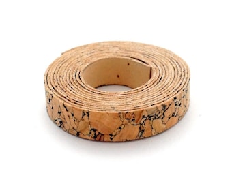 May include: A roll of cork ribbon with a natural brown and black marbled pattern. The ribbon is rolled up in a circle and is about 1 inch wide.