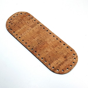 May include: A brown cork base with a rounded edge and holes around the perimeter. The base is made of a natural cork material.