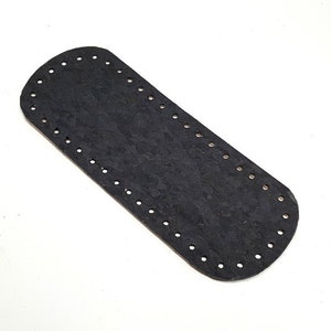 Könnte beinhalten: Schwarzer, ovaler Taschenboden mit gleichmäßig verteilten Löchern am Umfang zum Befestigen einer Häkel- oder Stricktasche. Der Boden besteht aus einem strukturierten Material und ist ca. 25 cm lang.