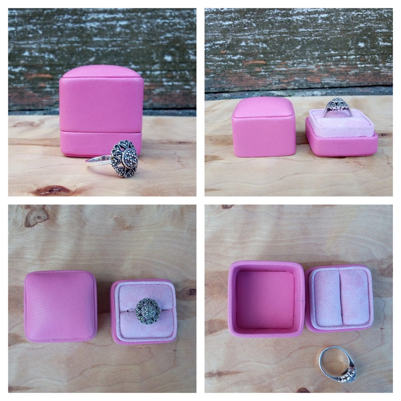 May include: A silver ring with a floral design and a pink ring box. The ring box is square and has a soft, velvet interior. The ring is displayed in the box, showcasing its intricate details.