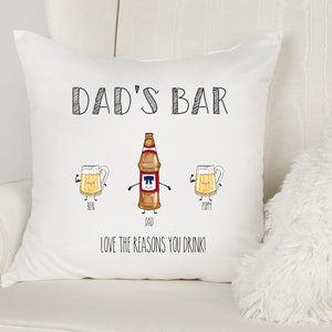 May include: White pillow with black text that reads "Dad's Bar" and a cartoon illustration of a beer bottle and two beer mugs. The text below the illustration reads "Love the reasons you drink!"
