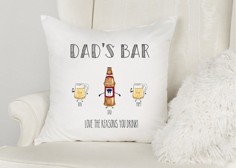 May include: White pillow with black text that reads "Dad's Bar" and a cartoon illustration of a beer bottle and two beer mugs. The text below the illustration reads "Love the reasons you drink!"