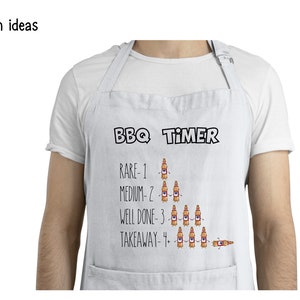 May include: White apron with a black and white graphic of a BBQ timer. The timer is a series of beer bottles with the text "RARE-1", "MEDIUM-2", "WELL DONE-3", and "TAKEAWAY-4".