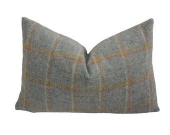 May include: A gray pillow with a plaid pattern in orange and yellow. The pillow is made of a soft, fuzzy material.