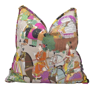 Peut inclure: Un coussin décoratif avec un fond beige et un imprimé coloré de personnes à cheval et d'éléphants. L'impression présente une variété de couleurs, notamment le rose, le violet, le vert, le bleu et le jaune. Le coussin est fait d'un tissu doux et confortable.