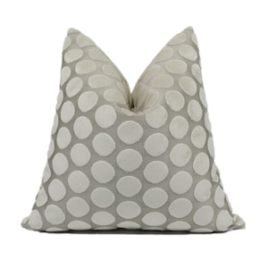 A gray and white polka dot pillow is shown against a white background.