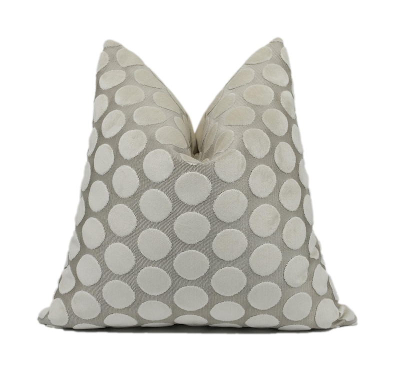 A gray and white polka dot pillow is shown against a white background.