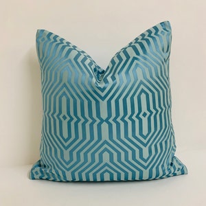 May include: A blue throw pillow with a geometric pattern. The pillow is made of a soft, luxurious fabric and has a subtle sheen.