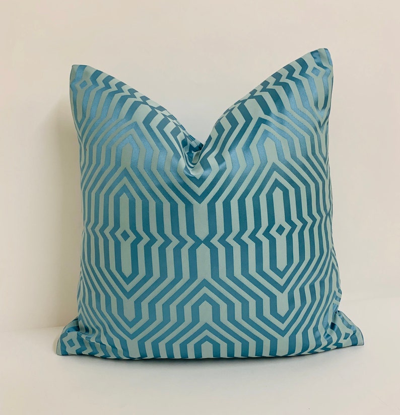 May include: A blue throw pillow with a geometric pattern. The pillow is made of a soft, luxurious fabric and has a subtle sheen.
